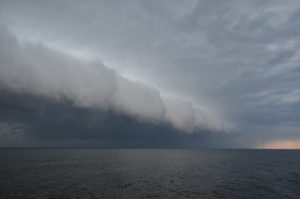 A shelf cloud -- large with a white facing and gray underneath -- rolls across Lake Ontario