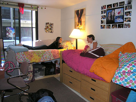 Two students lie on separate beds and talk in a residence halls